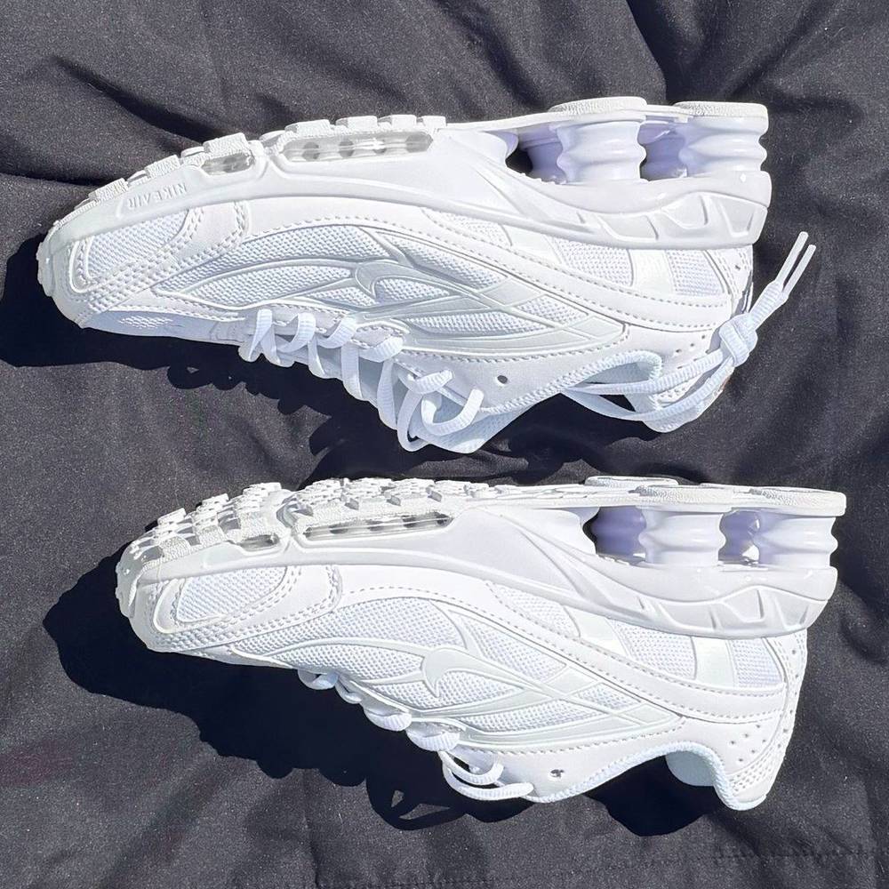 A pair of all white Nike Shox Ride 2 photographed on a dark cloth in daylight